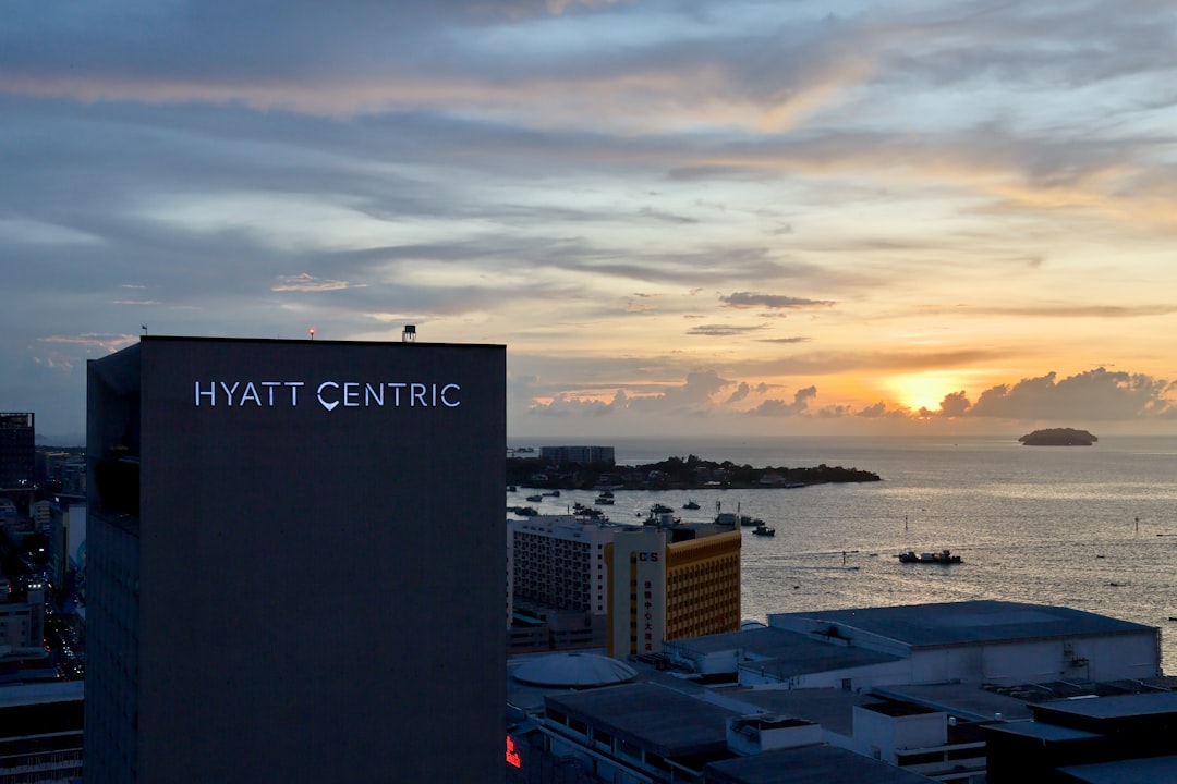 Hyatt centric building overlooks a coastal city at sunset.